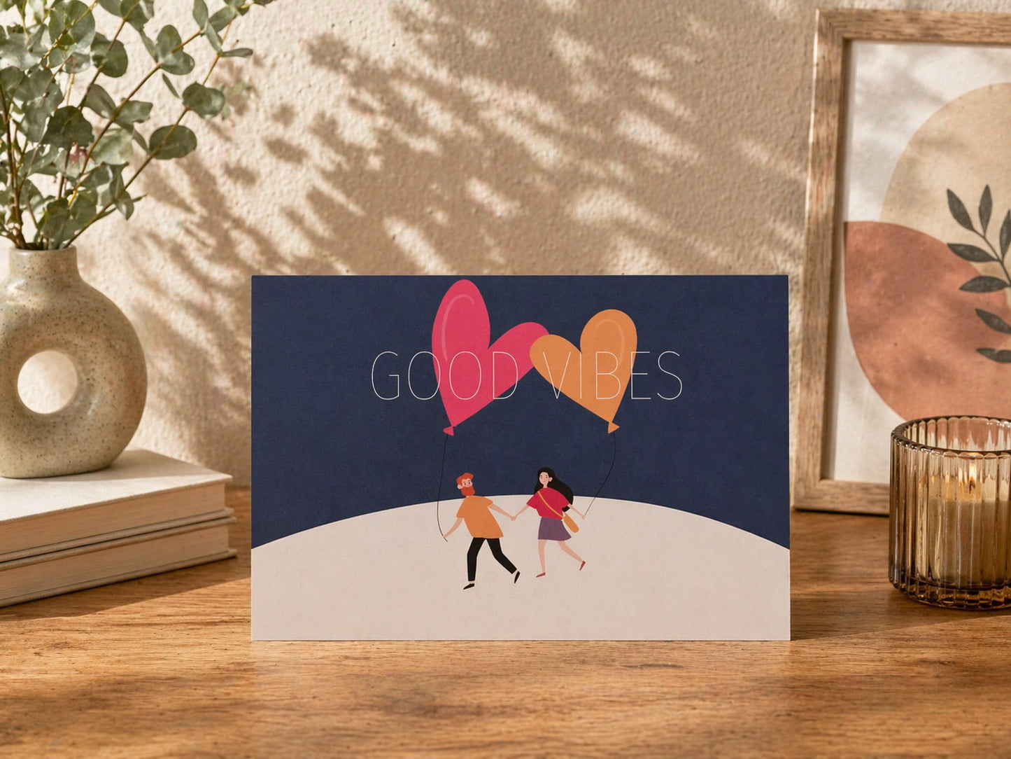 Greeting card with 'Good Vibes' text and heart-shaped balloons on a wooden surface.
