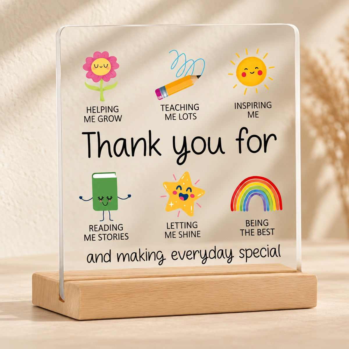 Teacher thank-you acrylic plaque with colourful flower, pencil, sun, book, star and rainbow illustrations on a wooden stand.