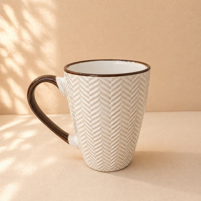 Ceramic mug with brown handle and chevron pattern on a beige background