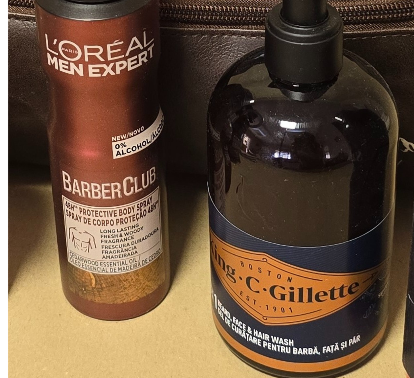 Men’s grooming and travel gift set in a brown leather Legacy toiletry bag filled with premium grooming essentials including deodorant, shower gel, shampoo, razors, and a rolled towel, styled on a wooden background with warm lighting.