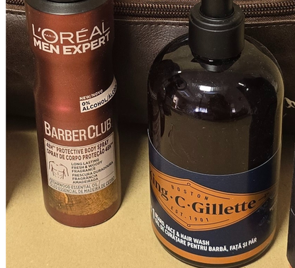 Men’s grooming and travel gift set in a brown leather Legacy toiletry bag filled with premium grooming essentials including deodorant, shower gel, shampoo, razors, and a rolled towel, styled on a wooden background with warm lighting.