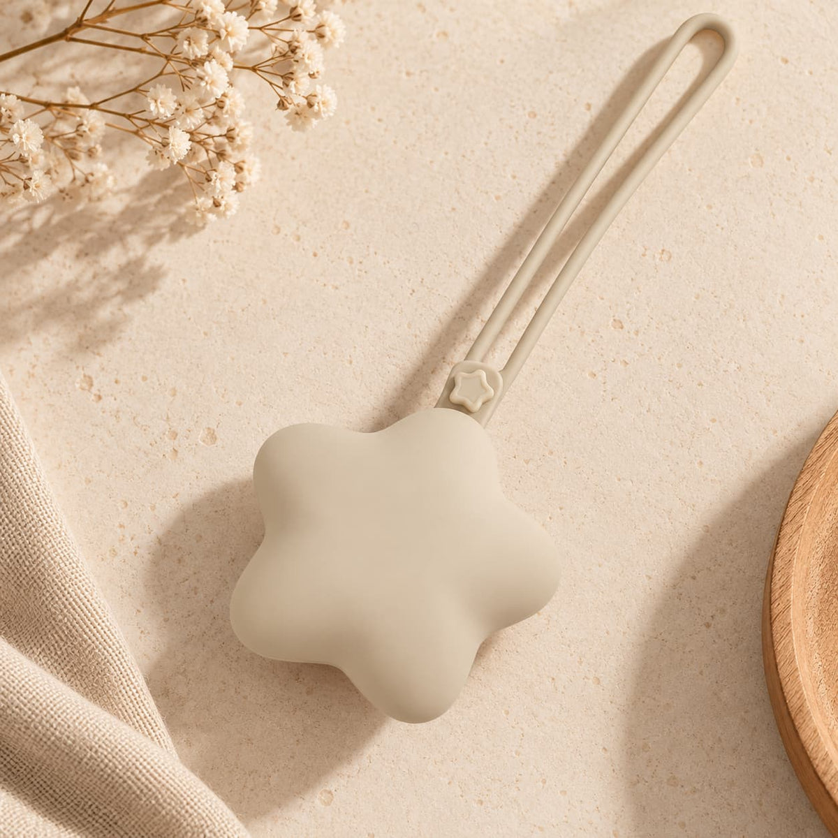 Grey star-shaped silicone baby pacifier holder case with long loop strap on a warm beige boho-minimal background.
