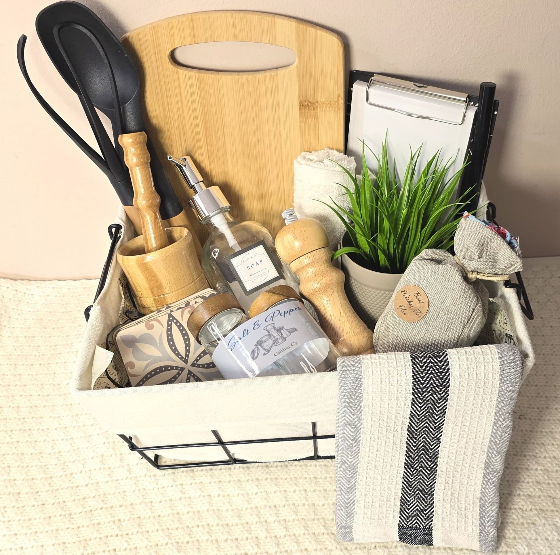 Kitchen Chef Gift Set in a wire basket with wooden cutting board, utensils, mortar and pestle, glass jars, towels, soap dispenser, and plant – perfect gift for food lovers and chefs