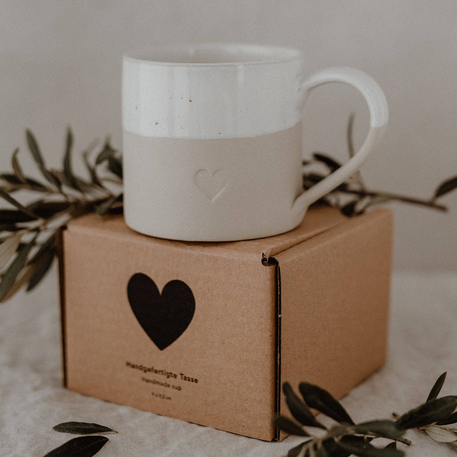 Large neutral stoneware mug with embossed heart detail, white glazed top and curved handle.
