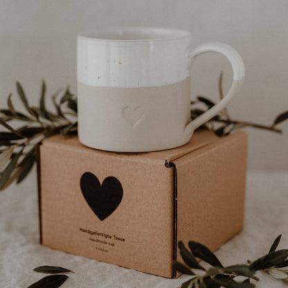 Large neutral stoneware mug with embossed heart detail, white glazed top and curved handle.