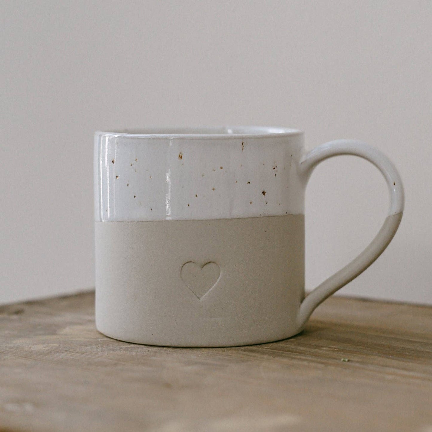 Large neutral stoneware mug with embossed heart detail, white glazed top and curved handle.
