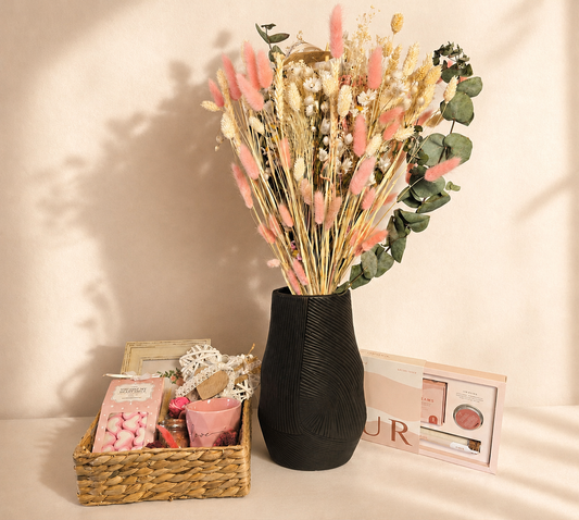 Luxury gift collection featuring a dried flower arrangement in a black vase, gift basket with sweets, personalised photo frame, and self-care essentials styled in elegant blush and neutral tones.