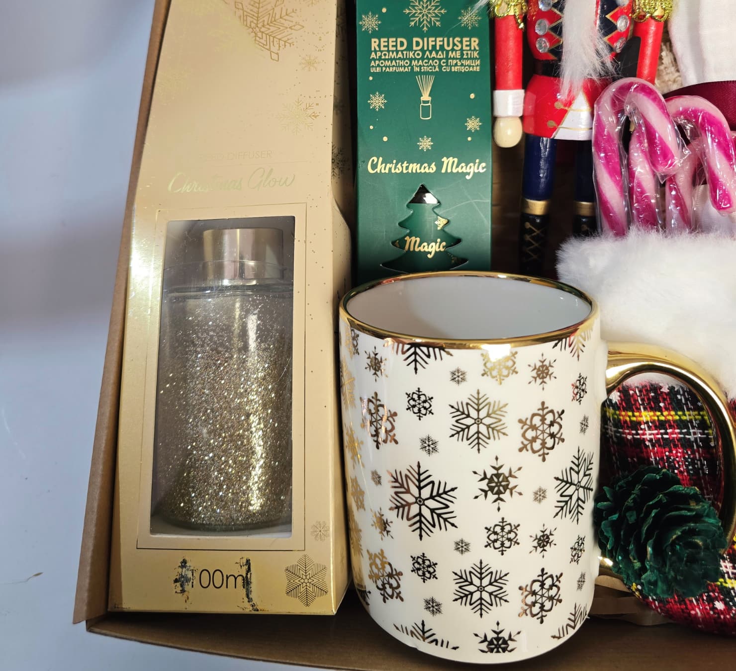 Magical Christmas gift box featuring a Nutcracker figure, gold snowflake mug, Christmas Magic reed diffuser, cozy fringed blanket, and Lindor chocolates.