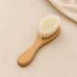 Natural wooden baby hair brush with soft cream bristles on beige linen fabric