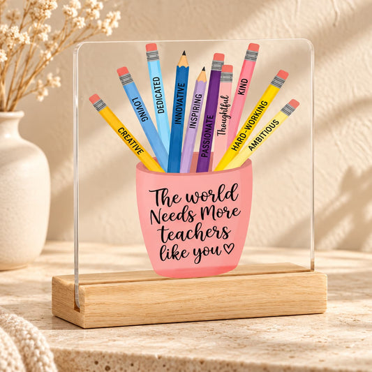 Teacher appreciation acrylic plaque with colourful pencils and "The World Needs More Teachers Like You" message on a wooden base, styled in a minimal boho setting.