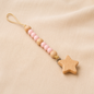 Pink and natural wooden bead pacifier clip with wooden star charm on cream fabric.