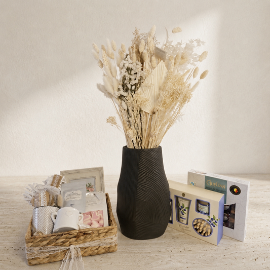 Luxury gift collection featuring a dried flower arrangement in a decorative vase, personalised photo frame, gift basket with treats, chocolates, and self-care essentials.