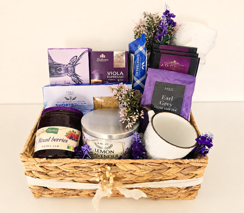 Purple premium corporate gift hamper with tea, coffee, chocolate, shortbread, jam, candle and mug in a woven basket