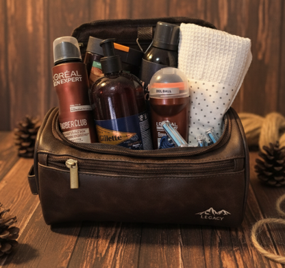 Men’s grooming and travel gift set in a brown leather Legacy toiletry bag filled with premium grooming essentials including deodorant, shower gel, shampoo, razors, and a rolled towel, styled on a wooden background with warm lighting. Gifting CY gift online shop cyprus and europe