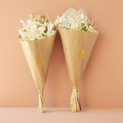 Two flower bouquets wrapped in brown paper with gold dots on a peach background