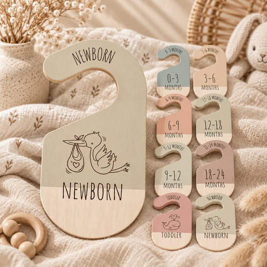 Wooden baby closet dividers in neutral boho colours with age labels from newborn to toddler, styled in a soft nursery setting.