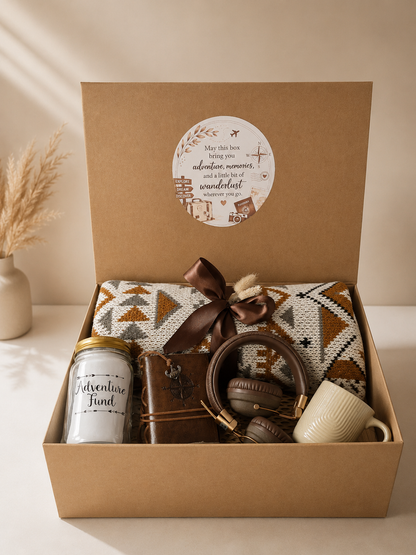 Travel gift box with a cozy patterned blanket, wireless headphones, adventure journal, travel fund jar, and coffee mug arranged in a kraft gift box against a vintage world map background. A thoughtful wanderlust-themed gift set designed for travel lovers and adventure seekers.