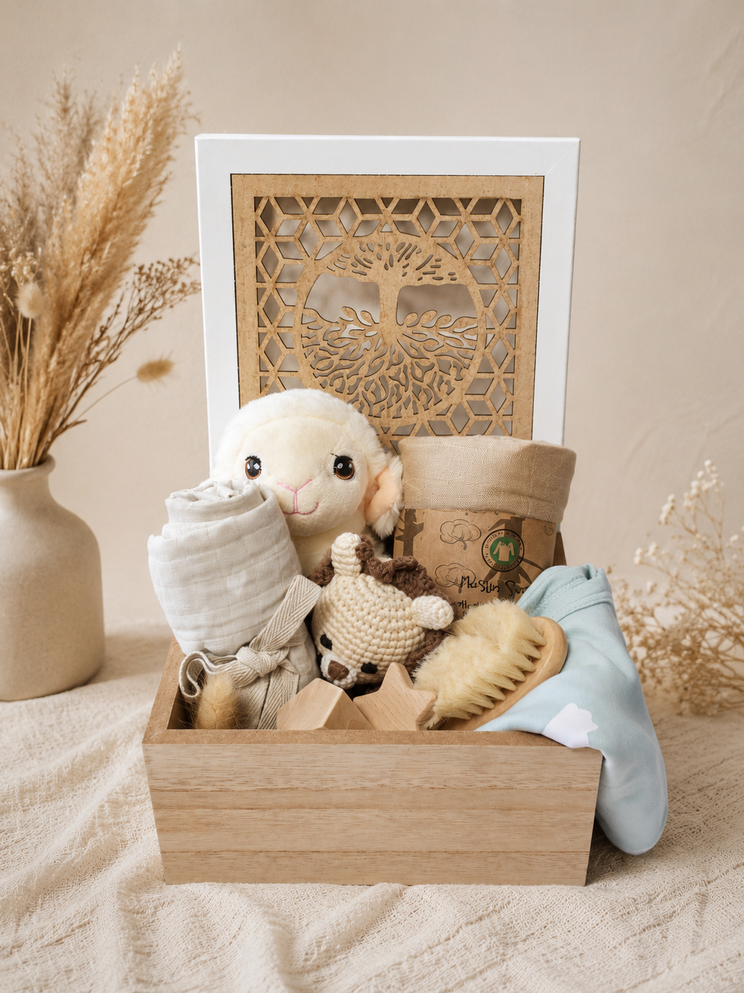 Personalized baby boy gift box with Tree of Life wooden keepsake box, plush lamb, muslin blanket, crochet toy, wooden teether, baby hair brush and soft blue baby essentials.