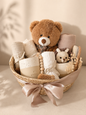 Minimal boho baby gift basket with brown teddy bear, neutral muslin cloths, ceramic baby keepsakes, wooden brush, crochet toy, dried flowers and blush ribbon.