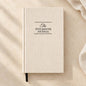Beige textured hardcover Five Minute Journal with black cover lettering and a black ribbon bookmark.