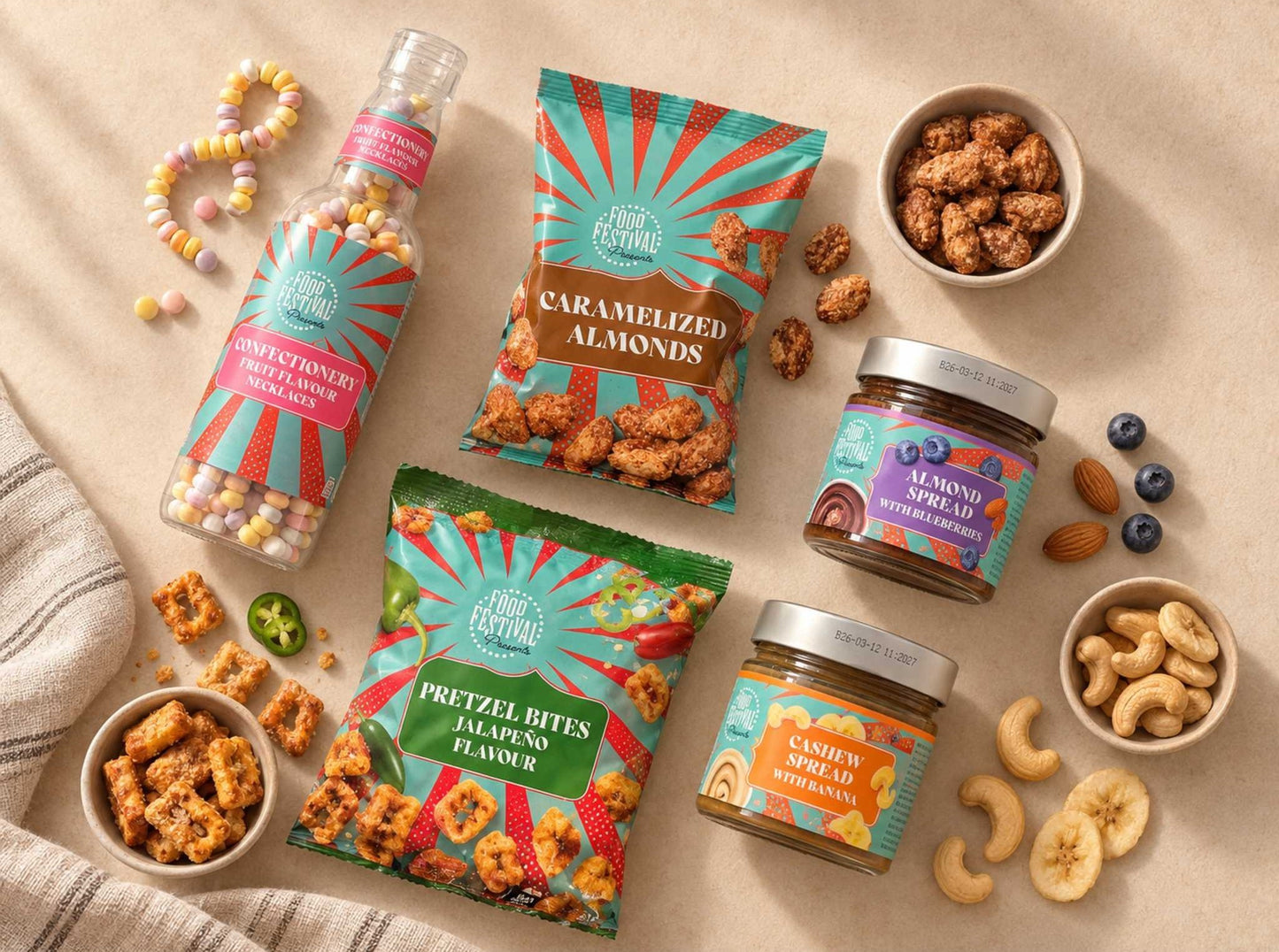 A styled flat-lay of Fresh Festival snack products on a beige surface, including a candy bottle, caramelized almonds bag, pretzel bites bag, lemonade spread jar, cashew spread jar, and nuts in bowls.