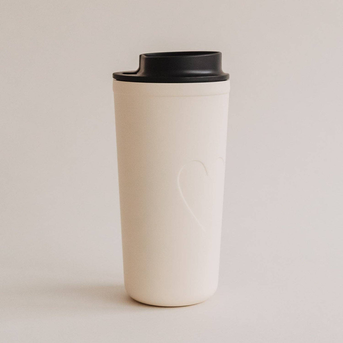 Cream 540 ml travel cup with a subtle embossed heart and black lid on a neutral background.