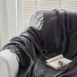 Luxury dark gray knitted throw blanket elegantly displayed in a cozy modern setting, packaged as a premium gift box for home décor and special occasions.
