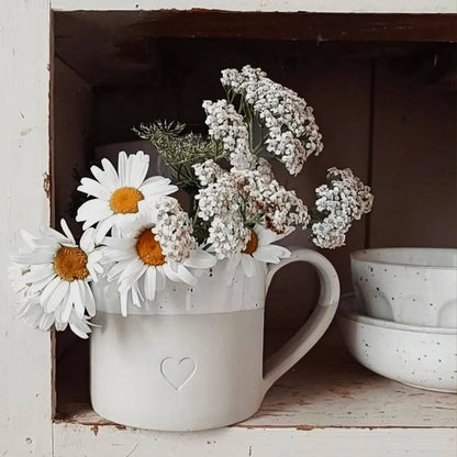 Large neutral stoneware mug with embossed heart detail, white glazed top and curved handle.