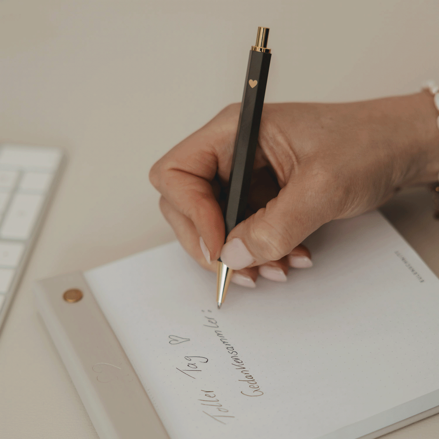 A hand writing in a notebook with the brown Eulenschnitt ballpoint pen.
