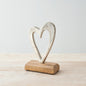 Abstract metallic heart ornament mounted on a wooden base, minimalist decorative piece on a light wooden surface.