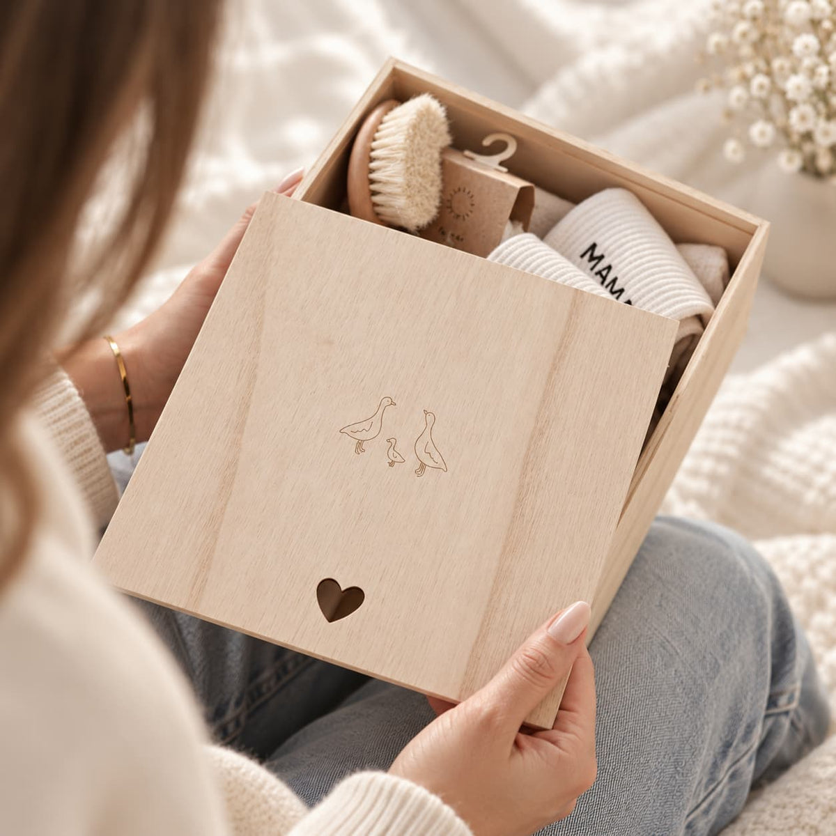 Pink newborn baby gift box in wooden keepsake box with muslin blanket, cotton onesie, brush, rattle and glass bottle
