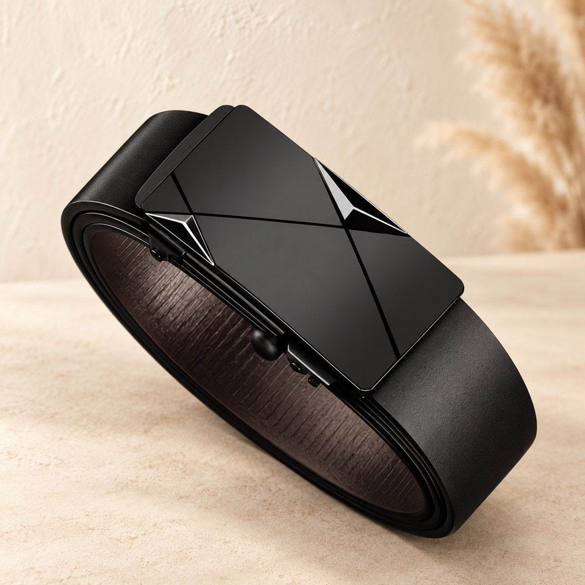Men’s black belt rolled to display a rectangular automatic buckle with a geometric design.