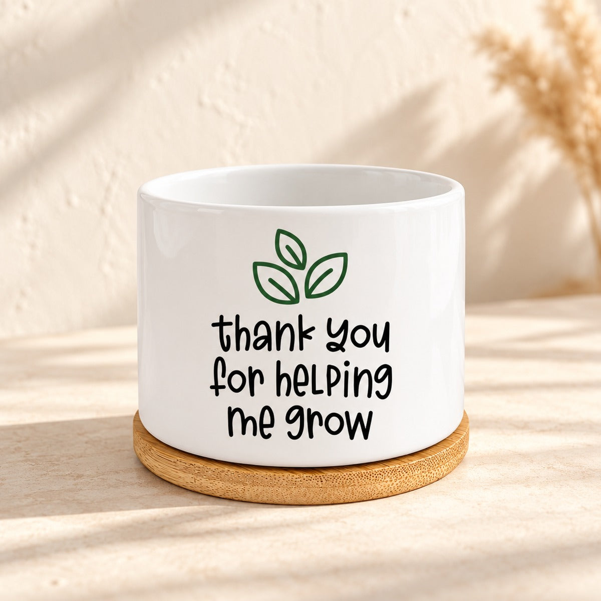 Empty mini white ceramic planter with green leaves and Thank you for helping me grow message, on a bamboo tray.
