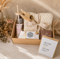 Luxury new mom gift box beautifully arranged on a marble surface, featuring a “Best Mom Ever” tumbler with bamboo lid and straw, cozy knitted blanket tied with a ribbon, floral hand cream, soft washcloth, decorative pampas grass, portable speaker, coffee sachets, and a greeting card, styled with neutral-toned flowers and elegant beige décor.