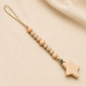 Beige and natural wooden bead pacifier clip with wooden star on cream fabric.