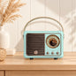 Retro portable speaker with gold-tone dial and carry handle, available in cream, sage green, blush pink and lilac.