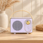 Retro portable speaker with gold-tone dial and carry handle, available in cream, sage green, blush pink and lilac.