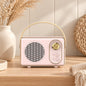 Retro portable speaker with gold-tone dial and carry handle, available in cream, sage green, blush pink and lilac.