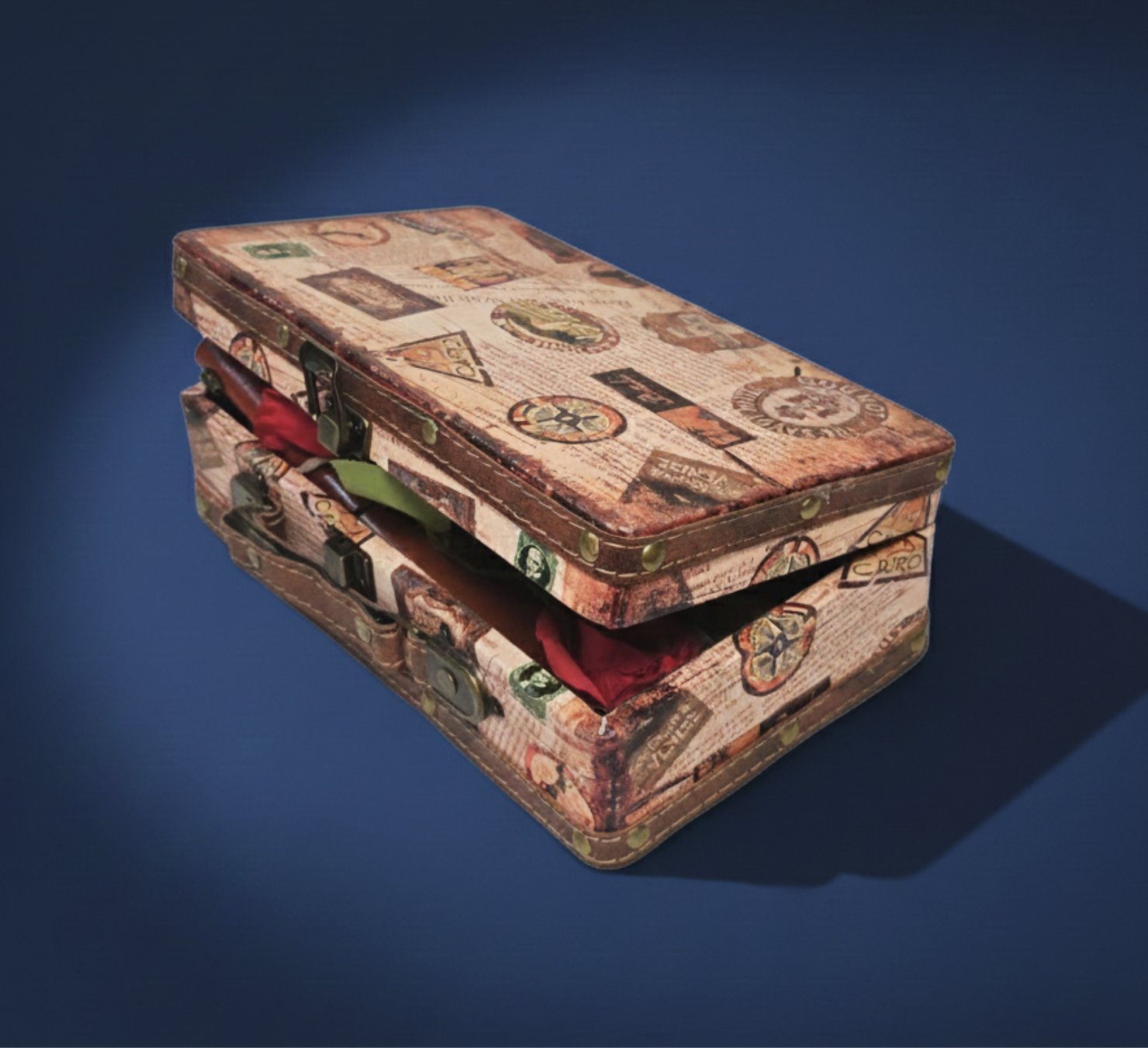 Vintage suitcase travel gift box containing a Lindt Swiss Classic chocolate bar, travel planner/sim book, and red artificial rose.