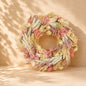 Luxury gift basket featuring a dried floral wreath, pink ceramic mug, wooden house keepsake, marshmallow gift box, and decorative home plaque arranged in a woven basket with a pink ribbon.