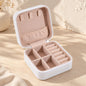 Open white mini travel jewellery case with blush lining, necklace hooks, ring rolls and divided compartments.